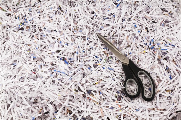 Black scissors on top of strips of shredded paper