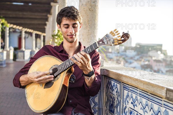 Fado musician playing on unique portuguese guitar in Alfama