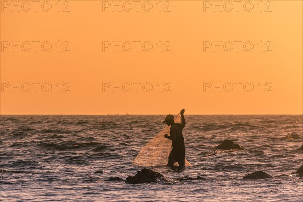 Local fishermen with fishing net in backlight