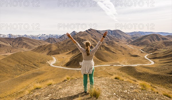 Woman looking at stark mountain landscape with mountain road