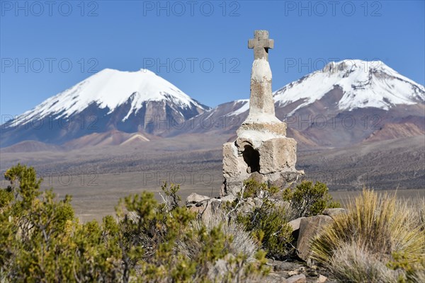 Snow covered volcanoes Pomerape and Parinacota with small chapel