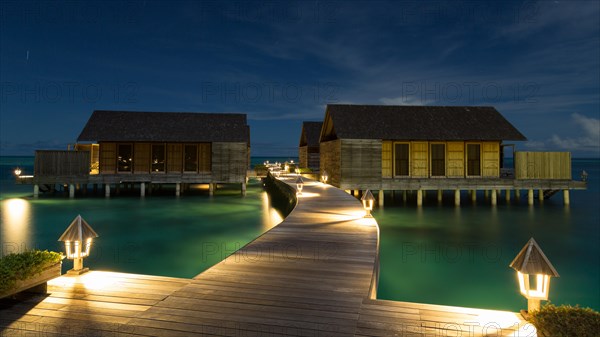 Wooden huts on stilts in lagoon at night