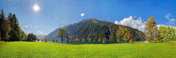 Green meadow with Lake Achensee and autumn-coloured deciduous trees