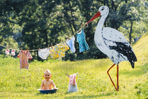 Baby bathing in a bowl in a spring meadow