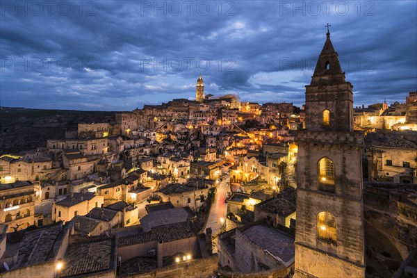 Church tower San Pietro Barisano in front of illuminated old town with cathedral