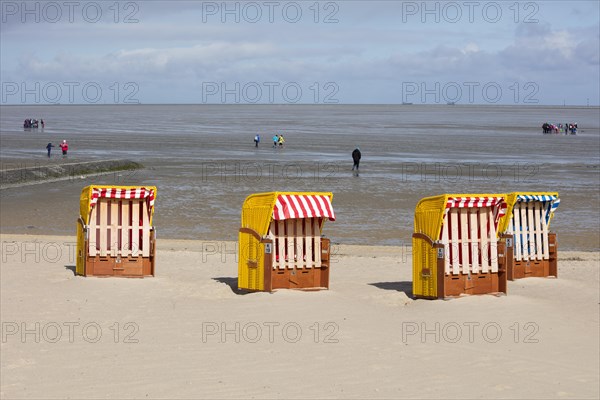 Beach chairs on sandy beach and back mudflat strollers