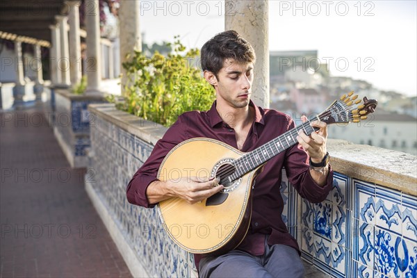 Fado musician playing on unique portuguese guitar in Alfama