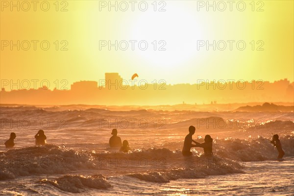 People bathing on the beach at sunset