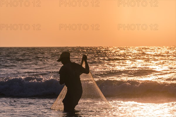 Local fishermen with fishing net in backlight