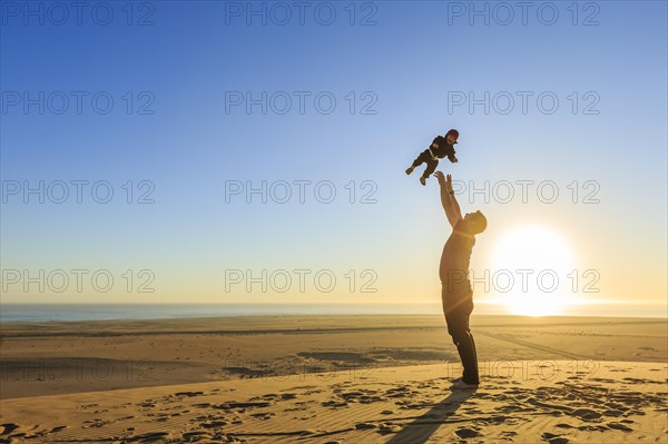 Father throws his little laughing son in the air