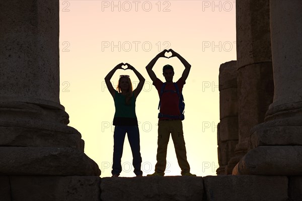 Couple forms a heart in sunset at the Temple of Hercules at the Citadel