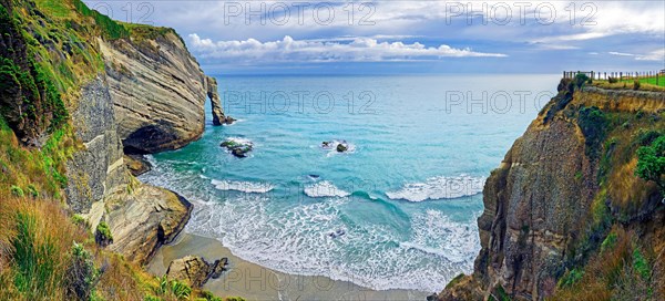 Steep cliff with arch of rock and small sandy beach