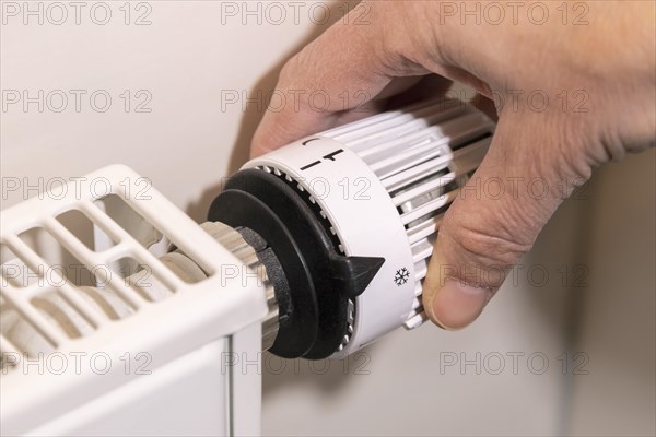 Hand adjusts the temperature at a thermostat of the heating
