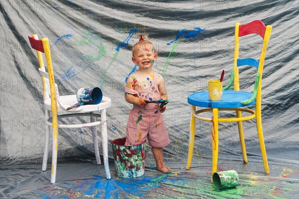 Four year-old girl standing with feet in paint pot