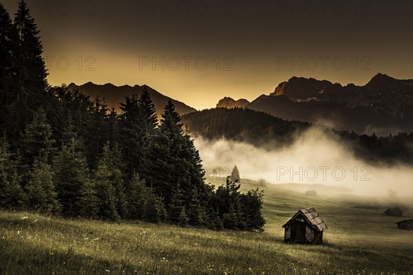 Small cabin on mountain meadow at forest edge