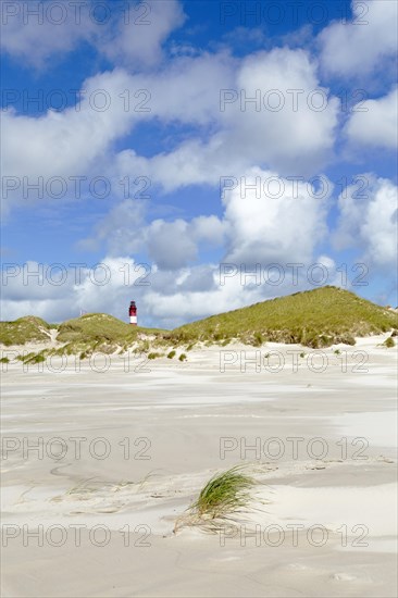 Dunes with lighthouse and cloudy sky