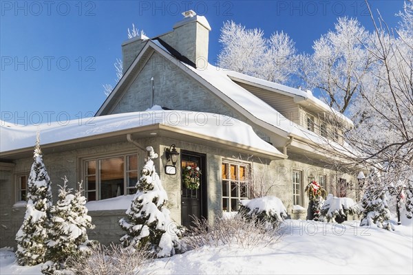 Old 1840s home facade with grey stone masonry and wood cladding plus Christmas decorations in winter