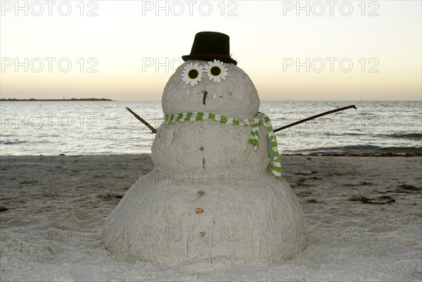 Snowman made of sand on the beach in the evening light