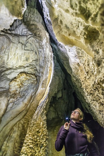 Woman lighting a cave with flashlight