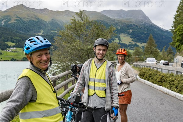 Three cyclists with mountain bikes and safety vest