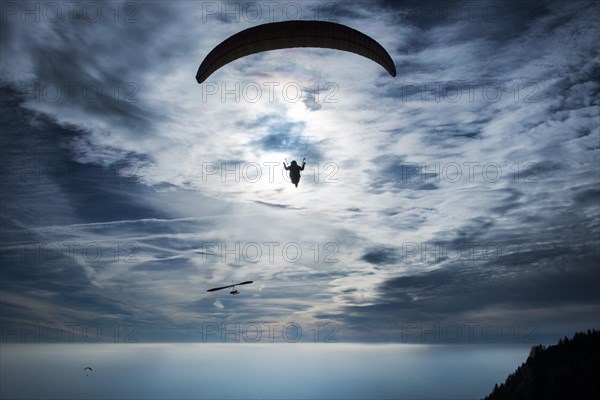 Paraglider against cloudy sky