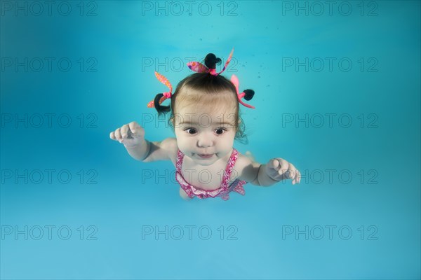 Little girl In a pink swimsuit diving in the swimming pool