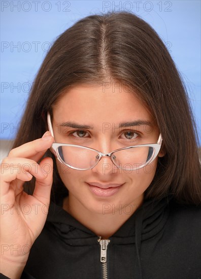 Young dark-haired woman looking over her eye glasses