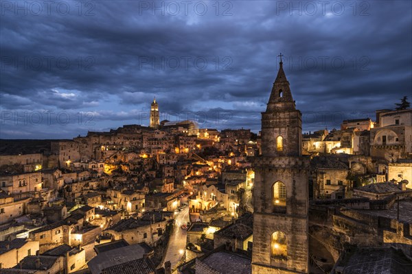 Church tower San Pietro Barisano in front of illuminated old town with cathedral