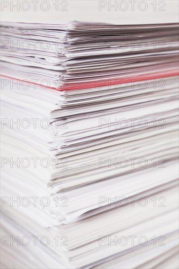Pile of stacked white paper reports with red one sticking out