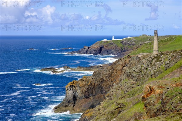 Rocky coast with old chimney from the Levant Mine and Pendeen Lighthouse