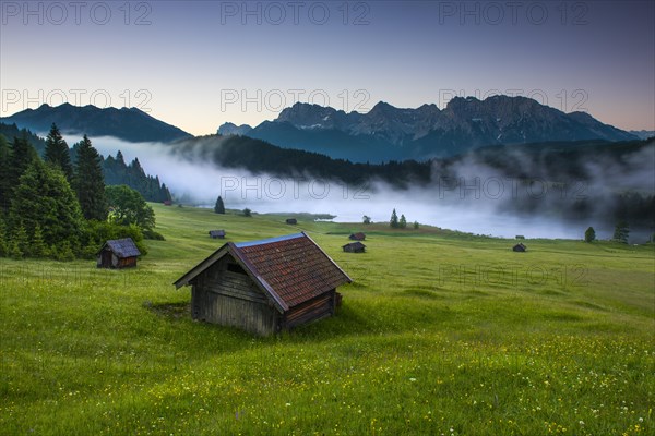 Small cabin on mountain meadow at forest edge