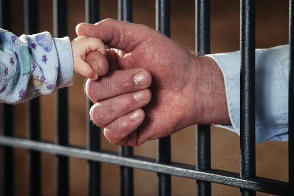 Hand of a prisoner holding a baby's hand