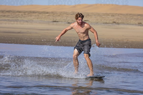 Young man skimboarding in the sea