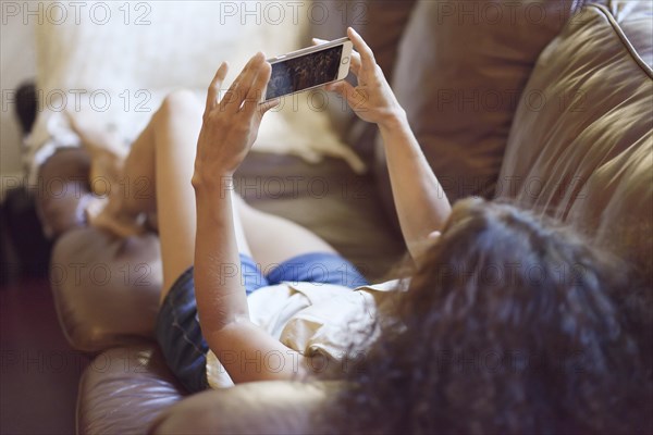 Woman lying on a sofa holding an iPhone in her hands