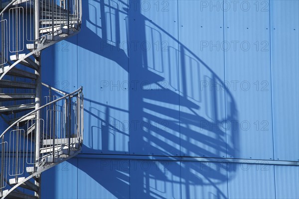 Spiral staircase and shadow on blue factory facade