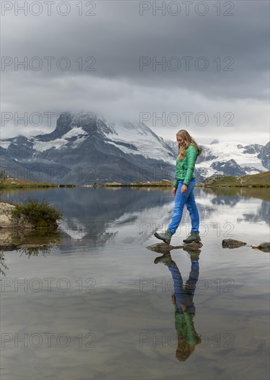 Hiker walks over stones in the water