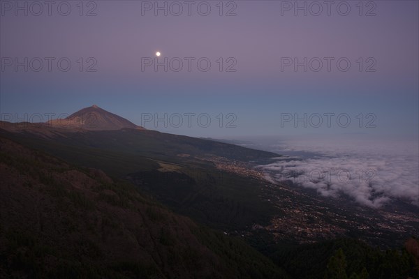 Night view of trade wind clouds over Orotava valley with Pico del Teide in front of sunrise
