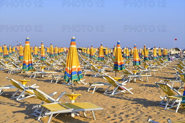 Beach with folded umbrellas and sun chairs