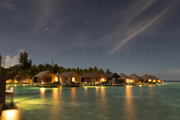 Wooden huts on stilts in lagoon at night