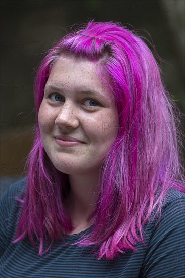 Portrait of a young woman with freckles and pink