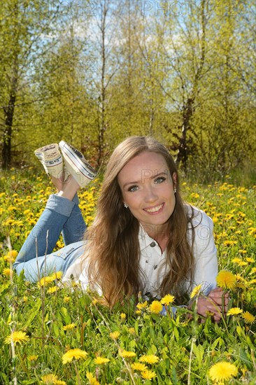 Young woman lying in a field of dandelion