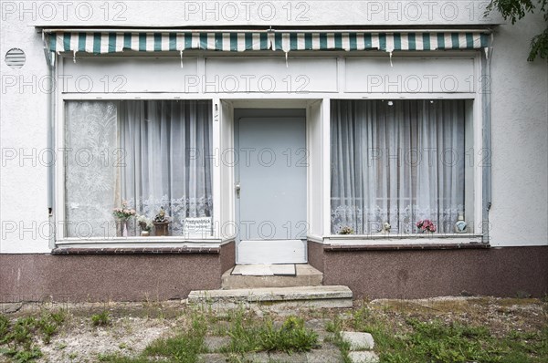 Dilapidated entrance with windows with old curtains