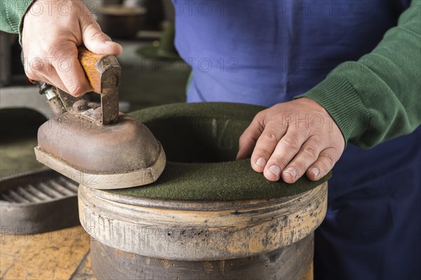 Ironing a dry wool felt hat over edge mold