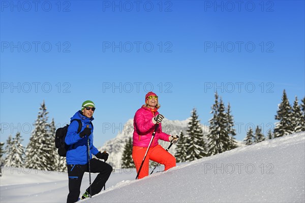 Two hikers walk through deep snow