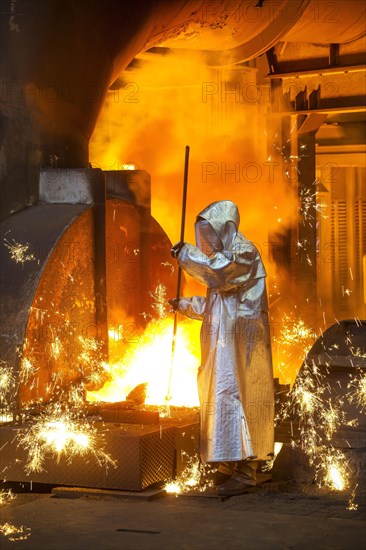 A steel worker in a protective suit taking a 1500 hot raw iron sample at the tapping