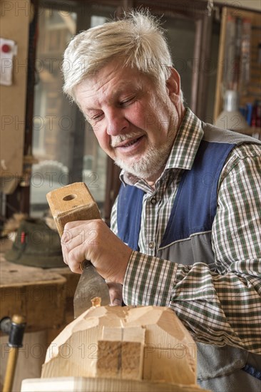 Wooden mask carver using wood carving tools on a wooden block