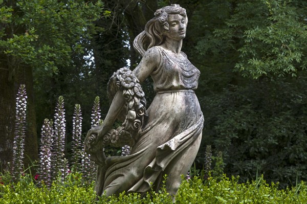 Female sculpture with a band of flowers behind acanthus