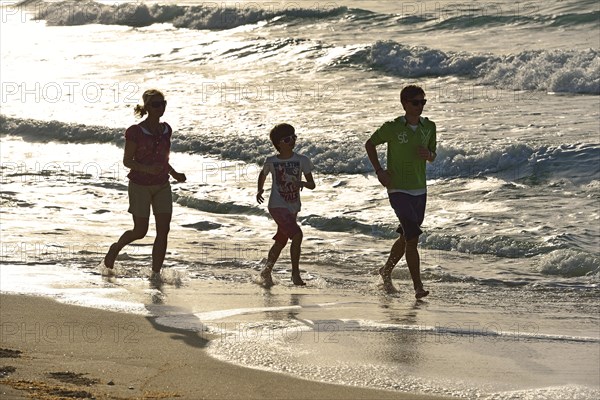 Family jogging on the sandy beach