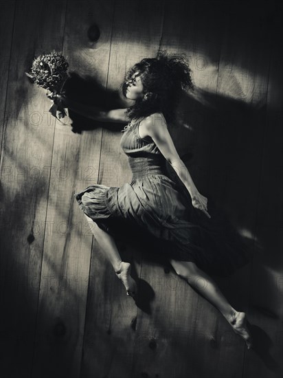 Young woman with a bouquet of wild flowers in a dynamic pose on wooden floor background