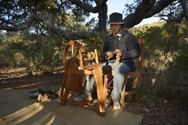 Woman weaving silk on spinning wheel from cocoons of silkworms